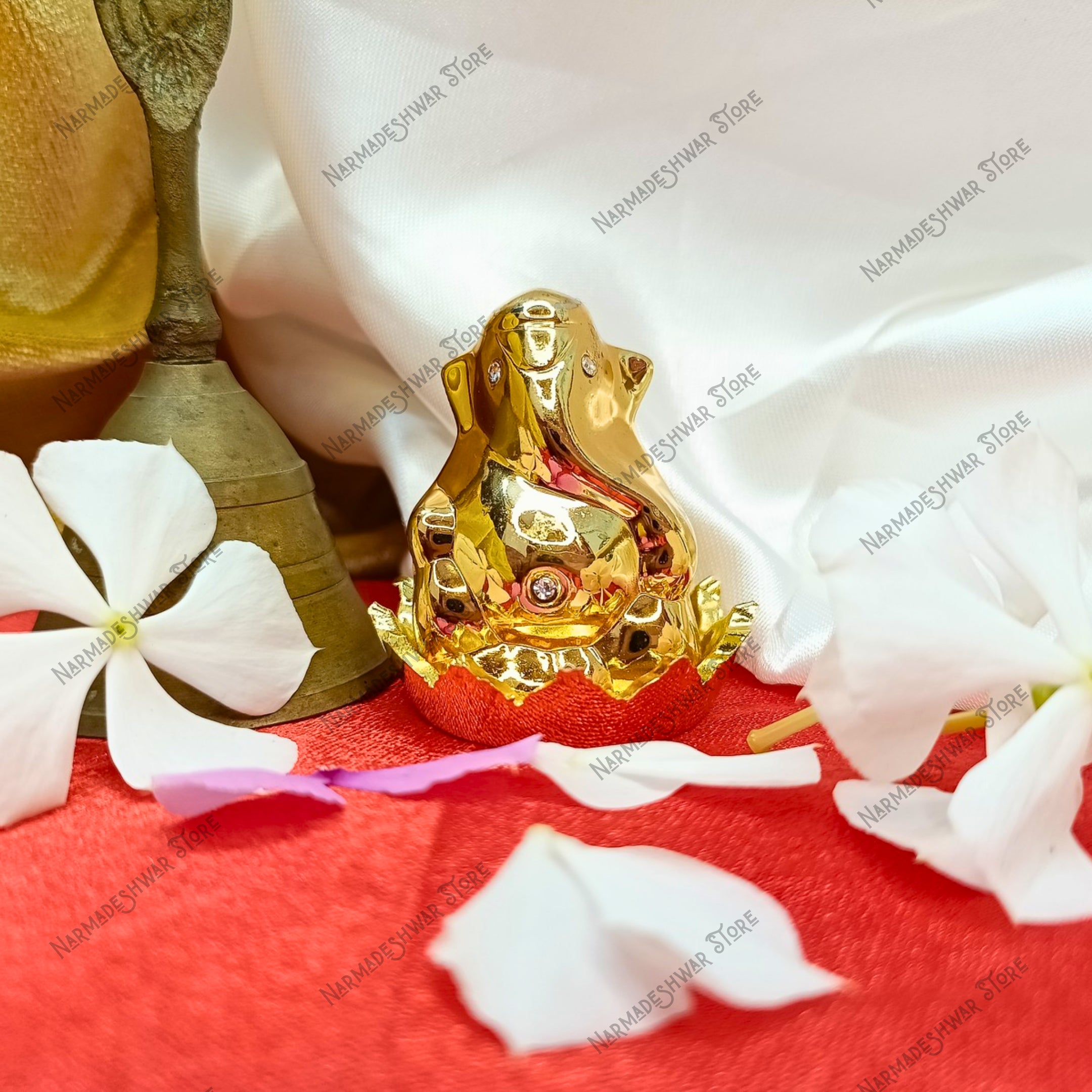 Golden Ganesh murti on a red surface with white flowers