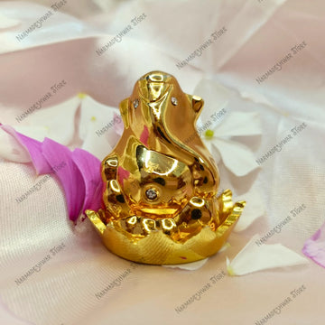 Golden Ganesh murti on a pink fabric background with flower petals.