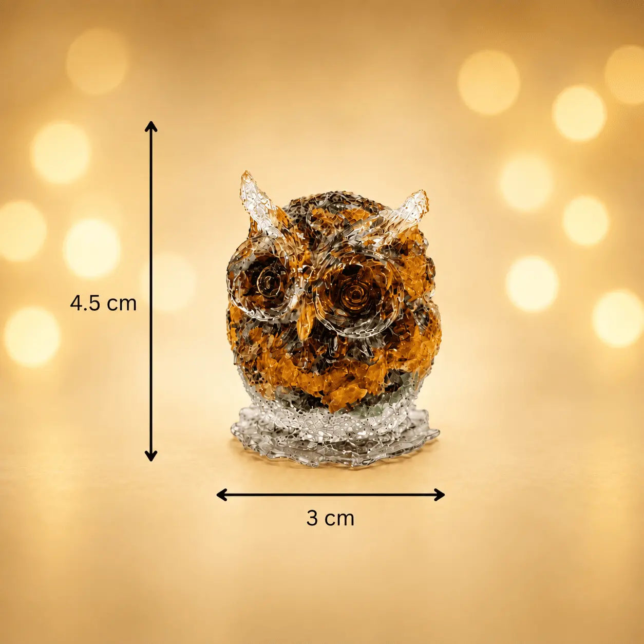 An owl-shaped decorative crystal sculpture on a glittery base, shown with dimension arrows indicating a height of 4.5 cm and width of 3 cm against a warm golden bokeh background.