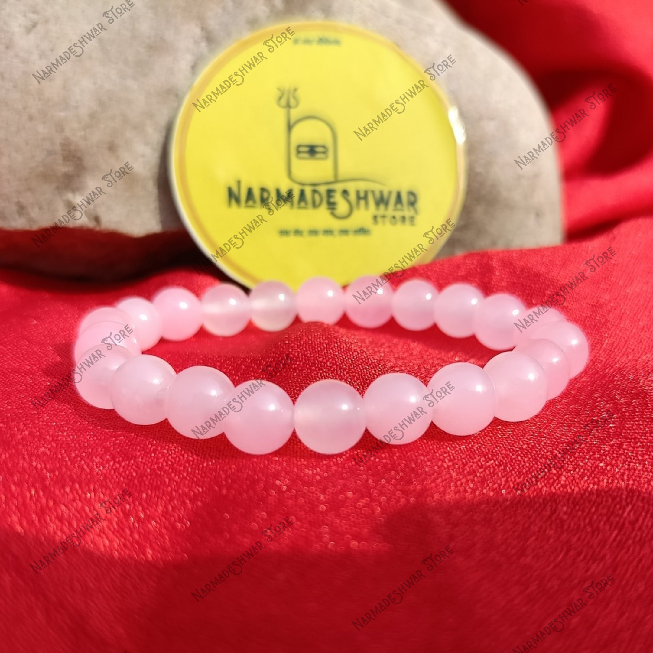 Rose Quartz emotional healing bracelet with brand tag on red satin backdrop
