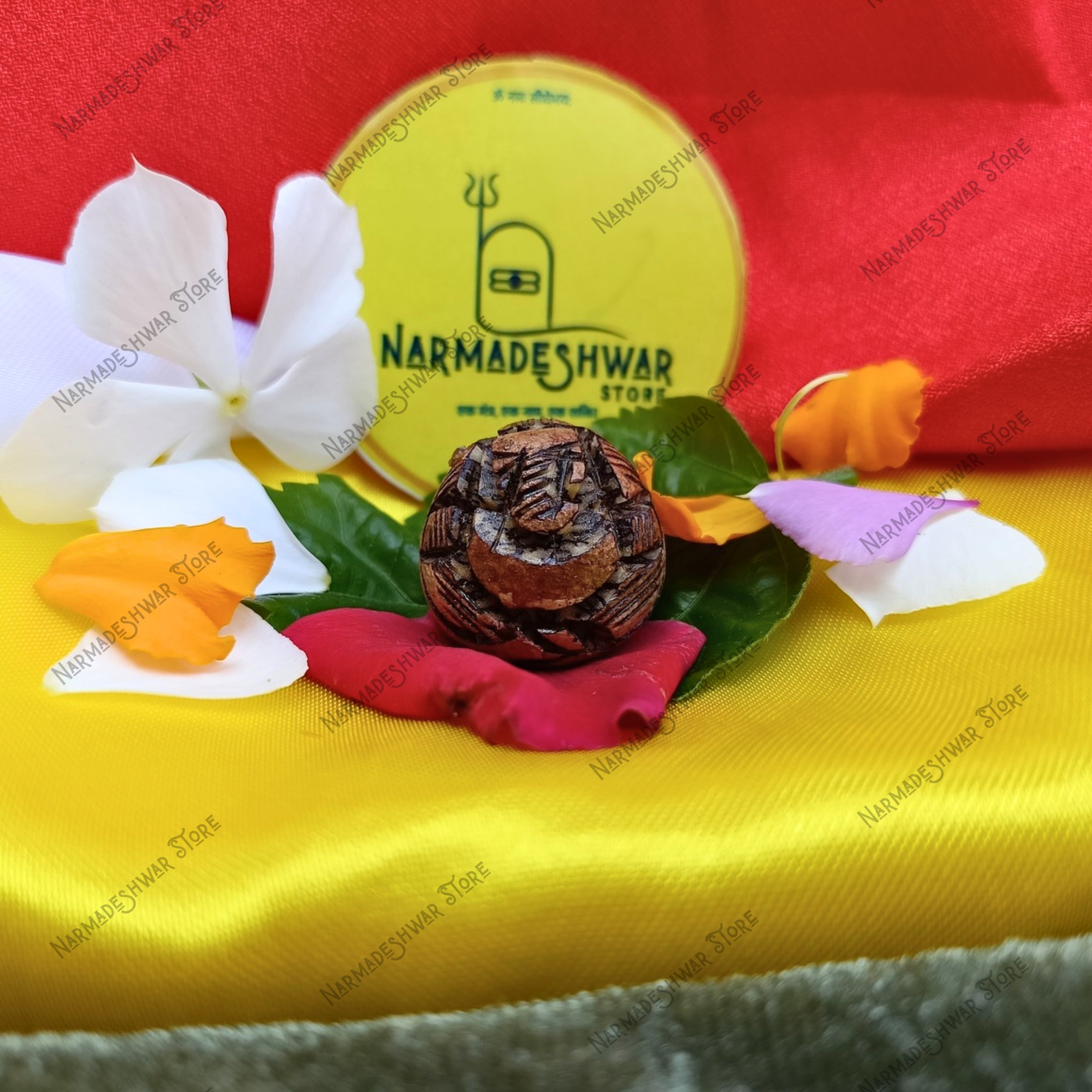 Supari Ganesh with flowers and leaves on a yellow surface, branded 'Narmadeshwar Store'.