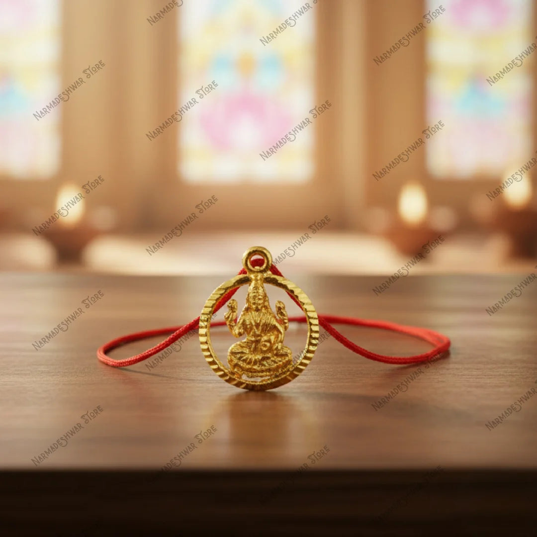 Lakshmi good luck locket with red thread on wooden surface